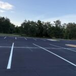 Crisp white parking stripes on freshly sealcoated asphalt under blue sky