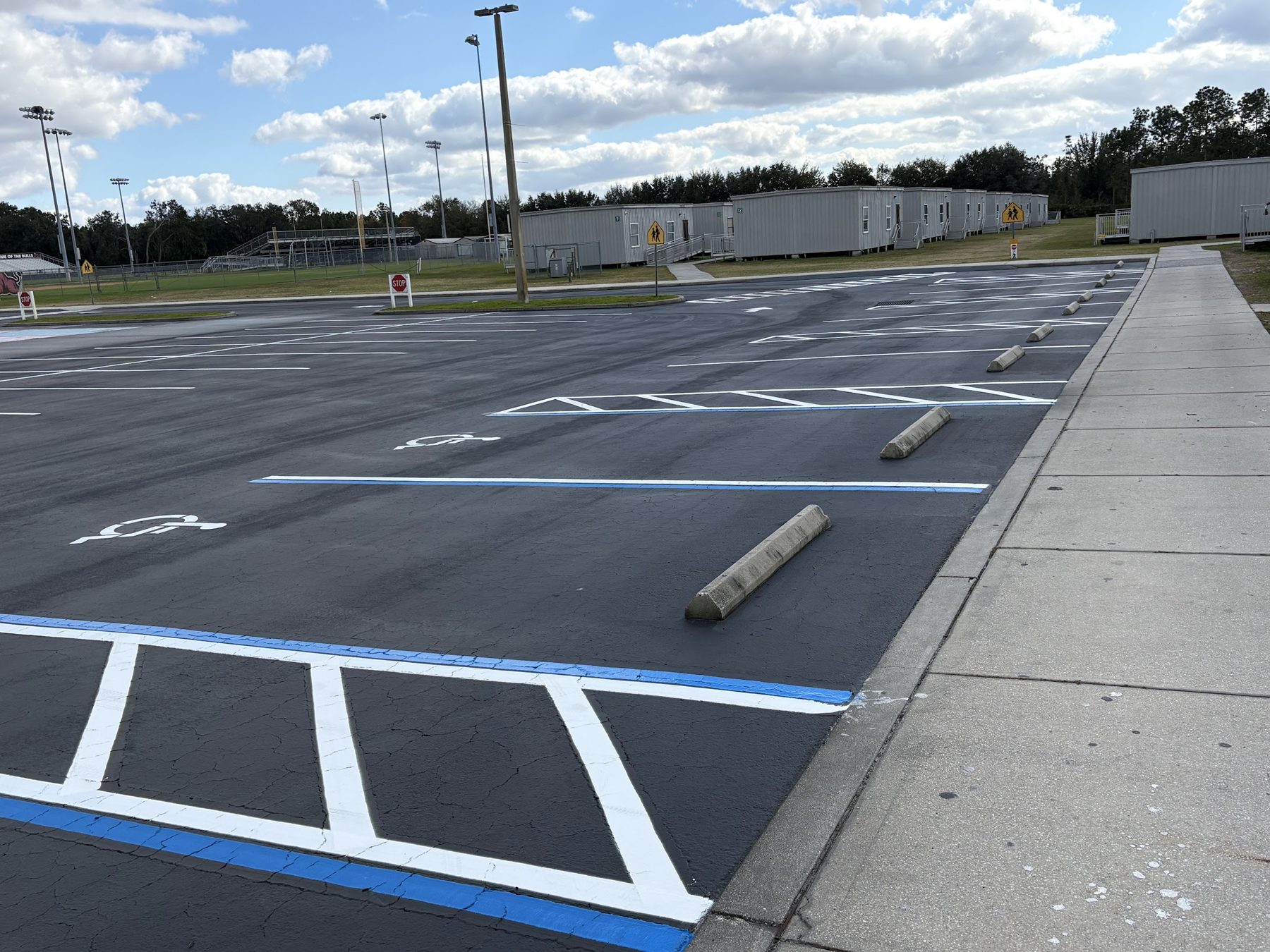 Fresh sealcoat with white striping, blue ADA lines and wheel stops